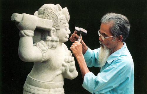 An artisan is working on a stone statue